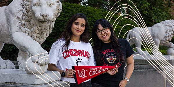 two students holding UC pennant 