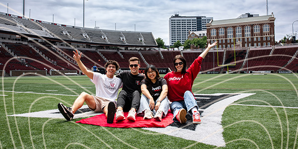 four students sitting on football field 